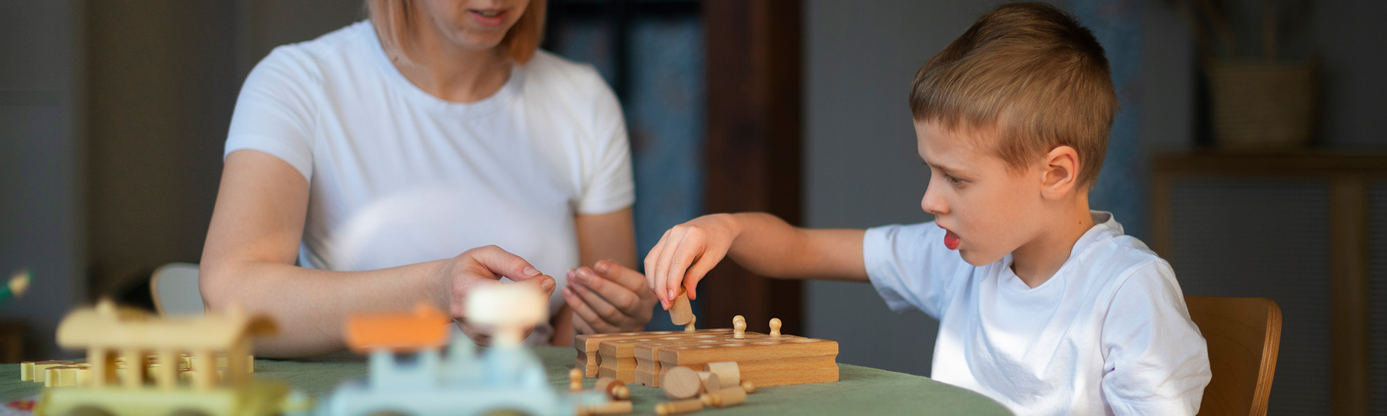 Kinder- und Jugendhospiz Leuchtturm Frau spielt mit autistischen Jungen mit Spielzeug